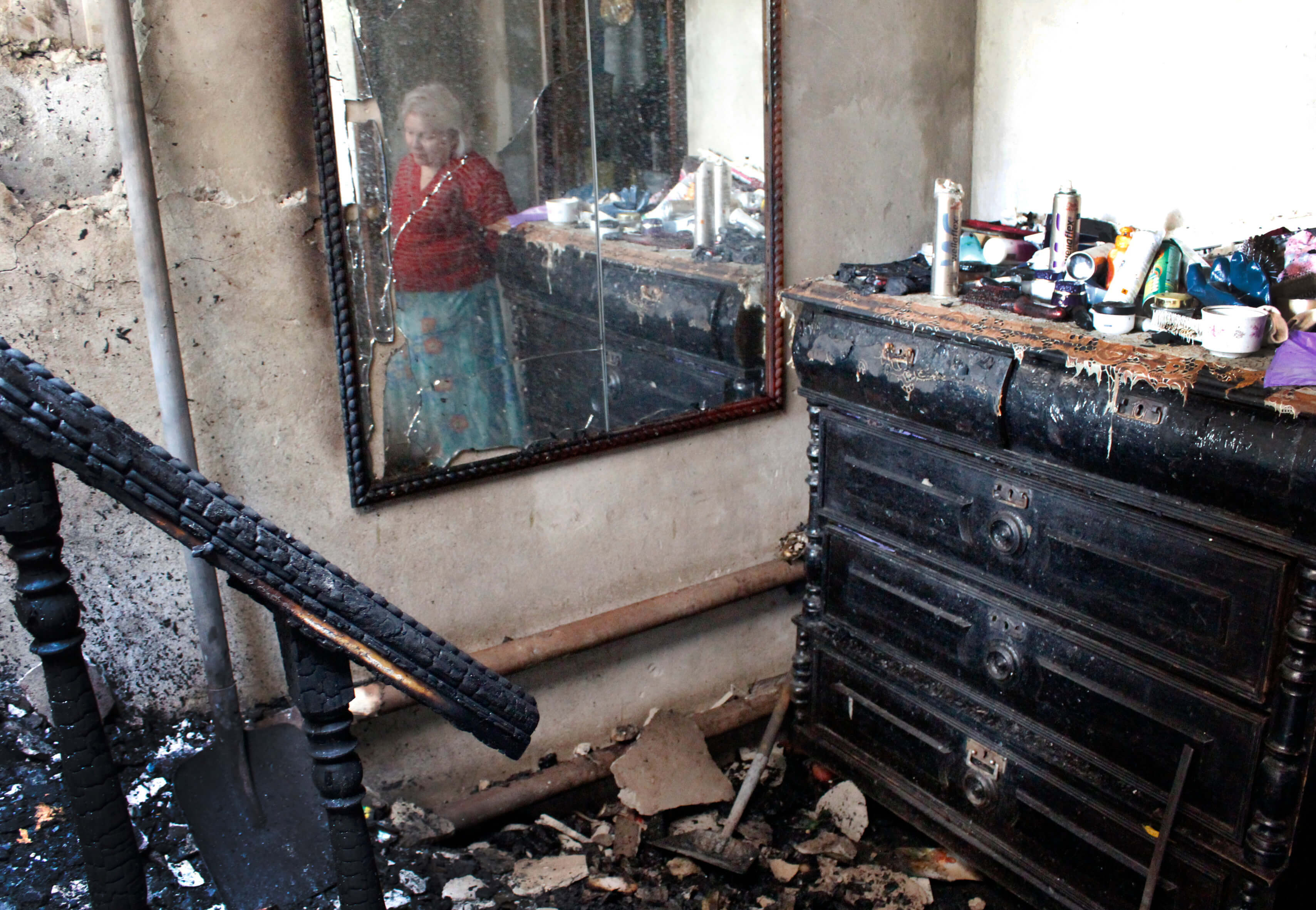 Montre le reflet d'une femme non identifiée dans une maison endommagée. Une des séries de photographies prises par le conseiller en réponse aux crises d'Amnesty International lors d'une mission de recherche en Ukraine au début de 2015.
